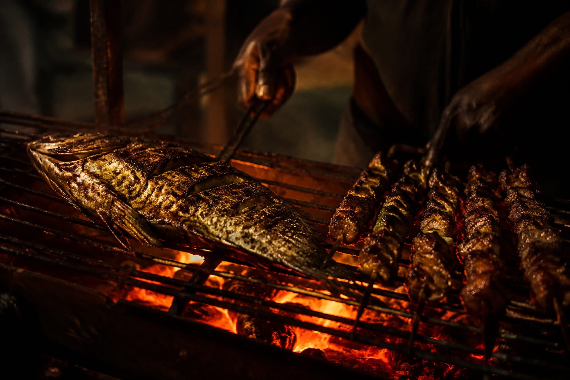 Poisson entier et brochettes sur des braises vives, pendant le service.